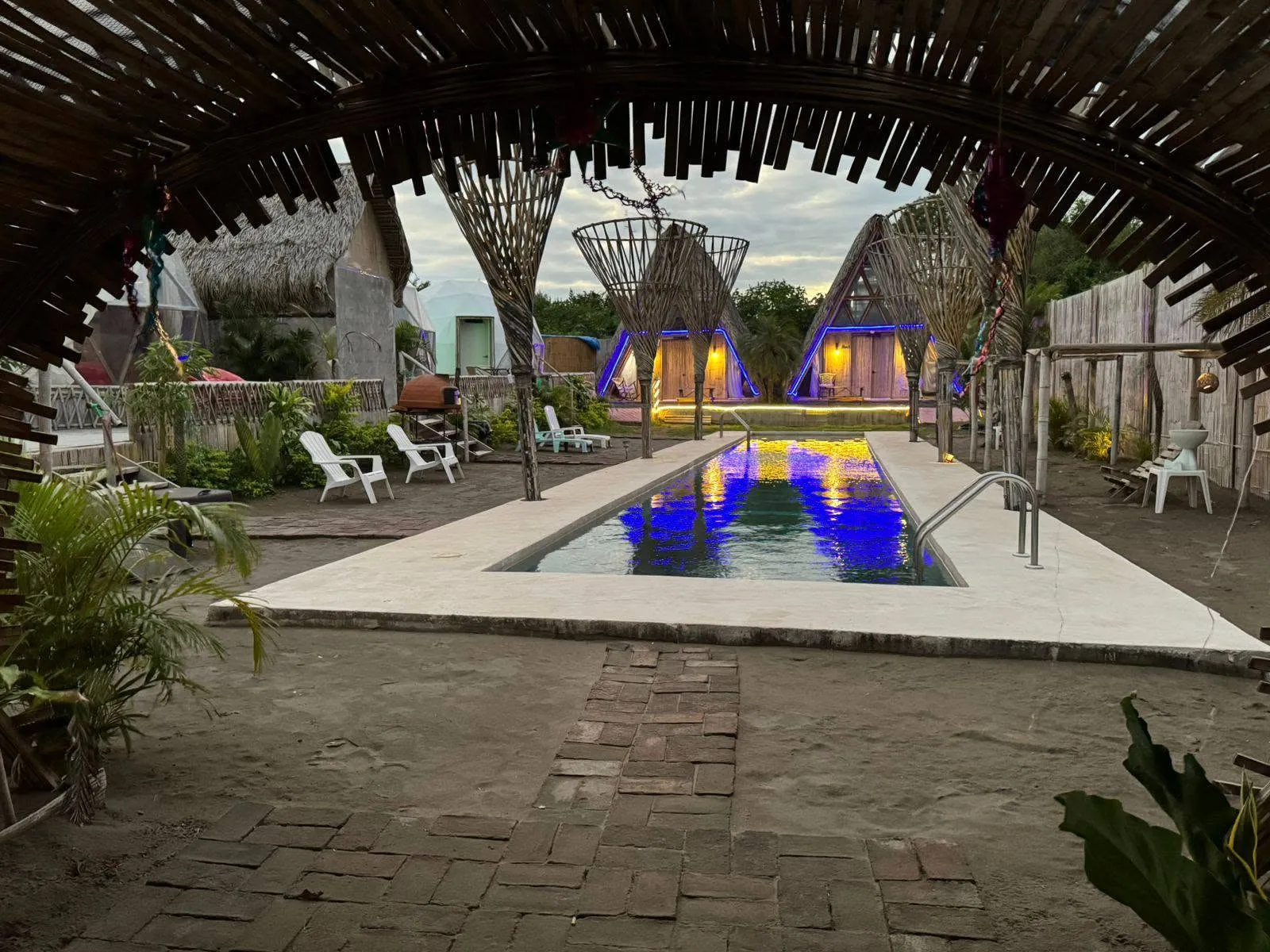 Alberca del glamping vista desde una palapa de bambú al atardecer